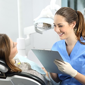 Smiling dental assistant taking notes on clipboard