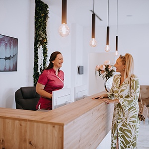 Patient and dental receptionist smiling together in lobby