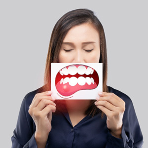 A woman holding an illustration of diseased gums in front of her mouth