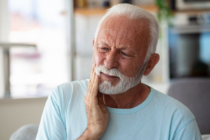 Older man holding jaw and looking uncomfortable