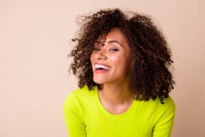 Woman in chartreuse sweater tilting her head and smiling