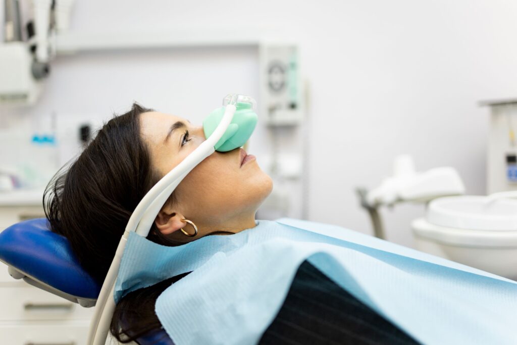 Profile view of woman with dark hair in dental chair with laughing gas mask